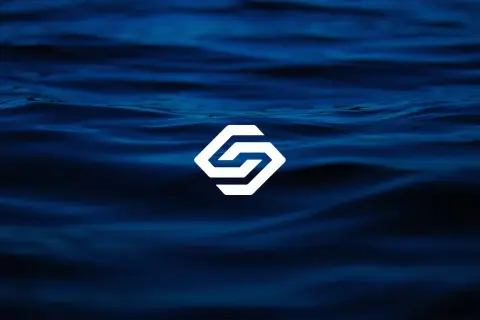 A dark blue underwater photograph showing variations in water depth captured through subtle gradients and textures. A centered white geometric logo spans the image horizontally, its edges crisp and well-defined against the deep marine blues of the background. Underwater photography with high contrast lighting and sharp focus on surface patterns.